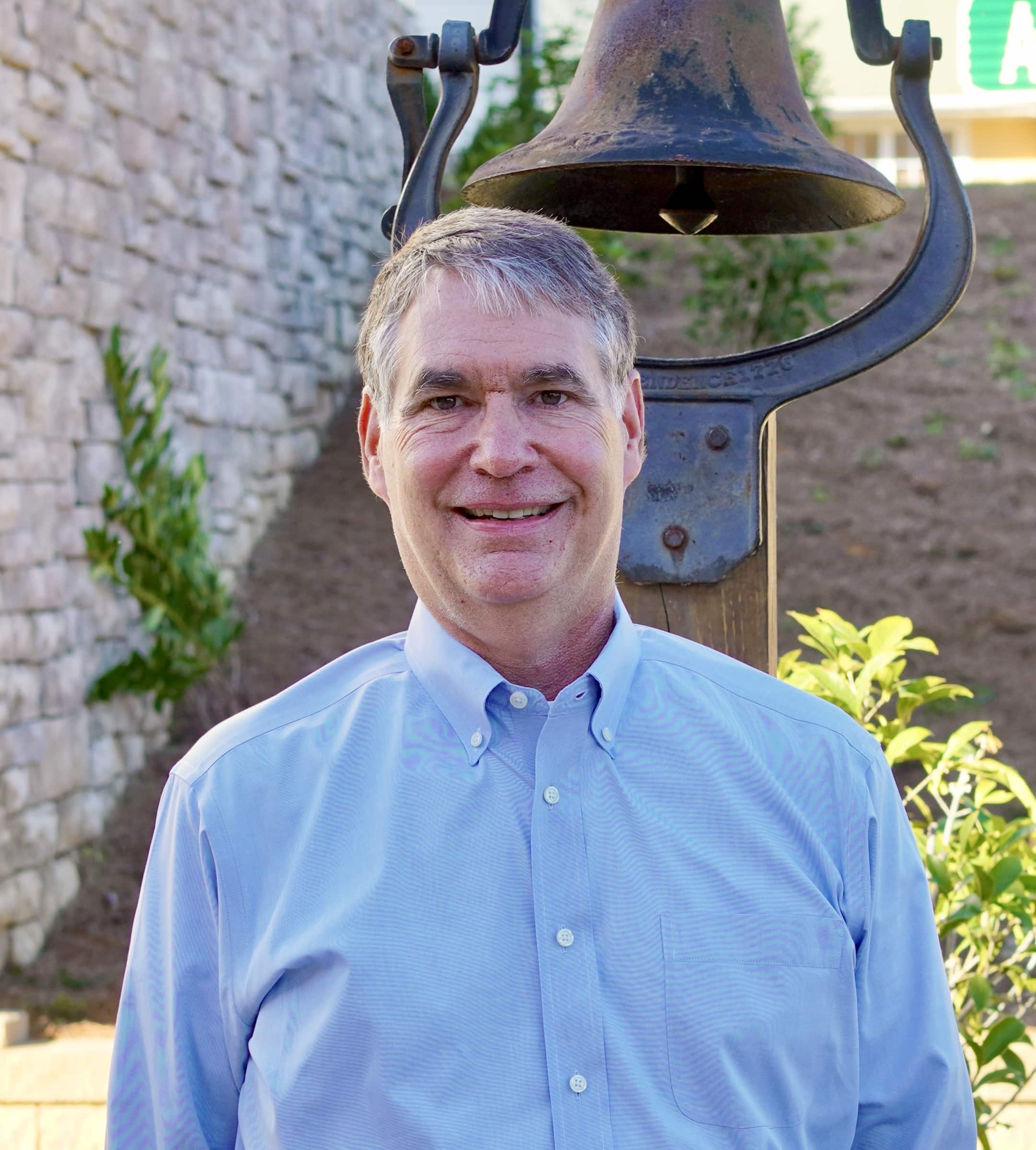 Executive Director Ben Tison standing in front of No Longer Bound bell.